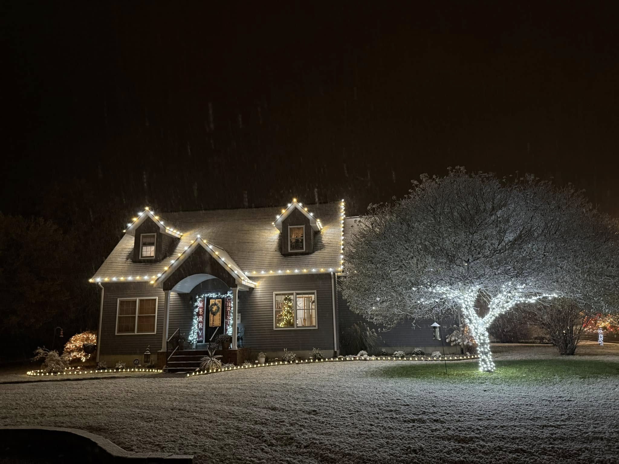 Home glowing with warm white holiday lights during snowfall