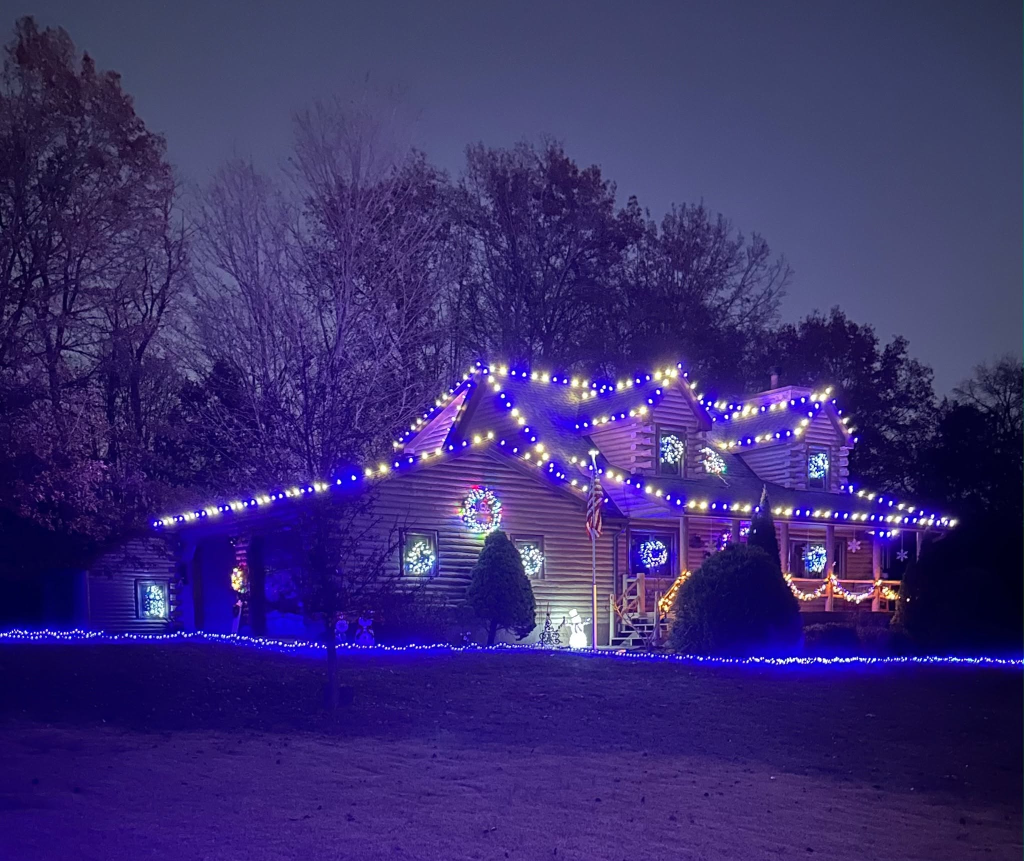 Snowy home with warm white roofline and landscape lighting