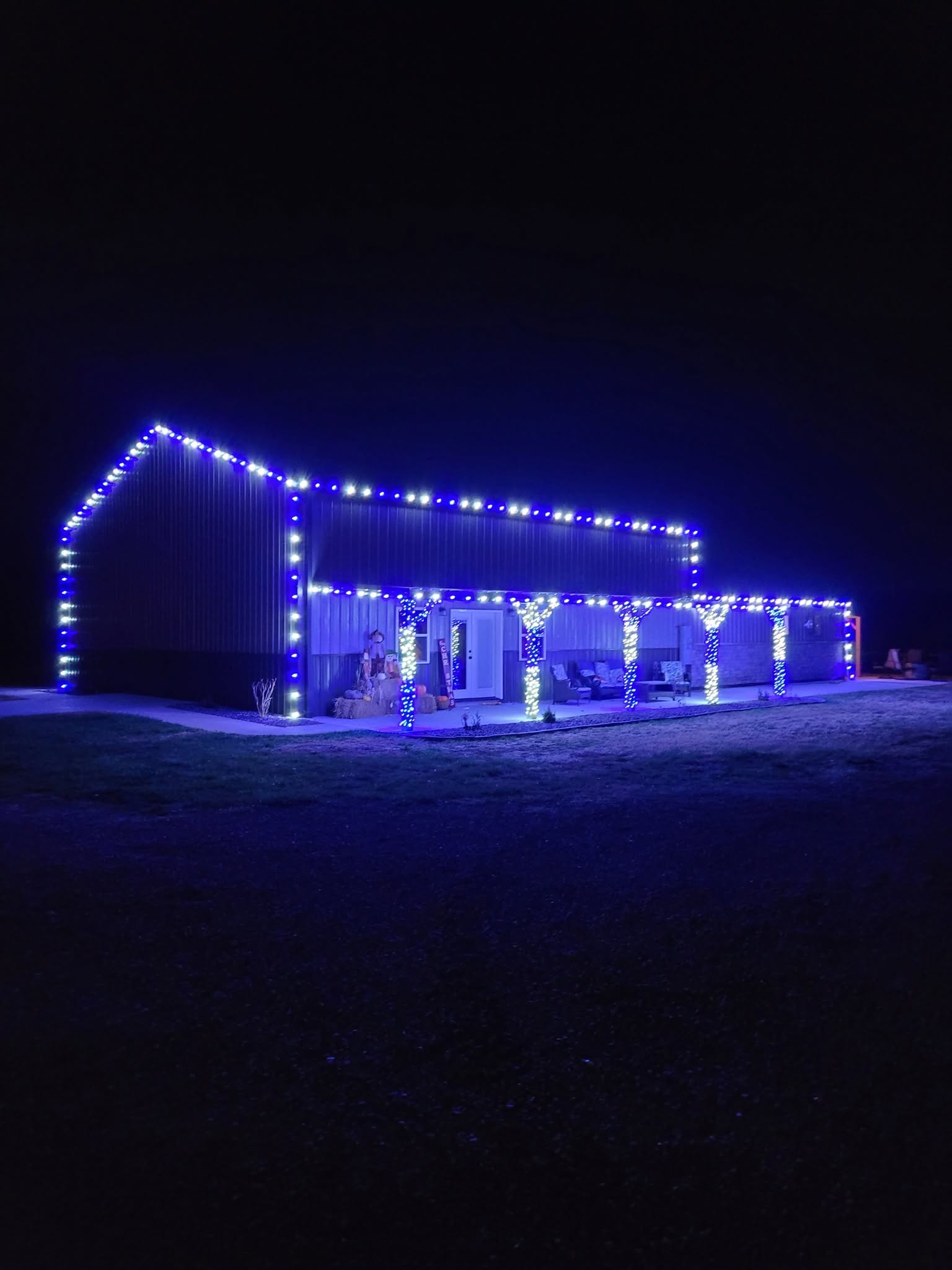 Country home illuminated with blue and white holiday lights