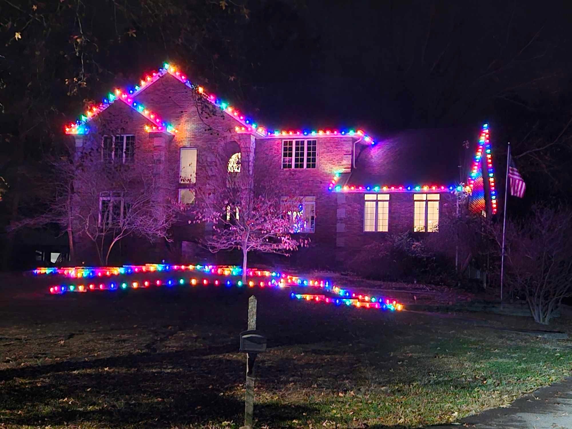 Brick home decorated with bright multicolor roofline lights