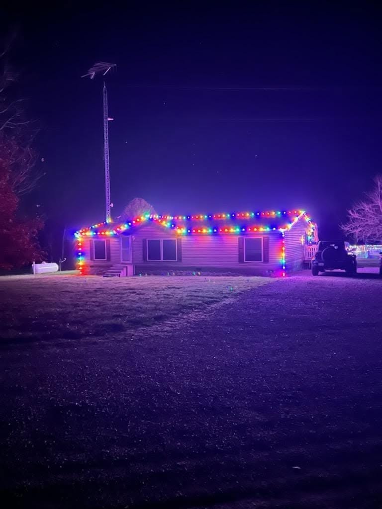 Country home glowing with multicolor roofline lights