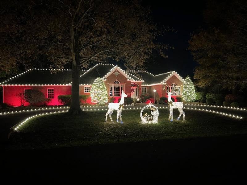 Home with warm white roofline lights, red uplighting, and illuminated reindeer