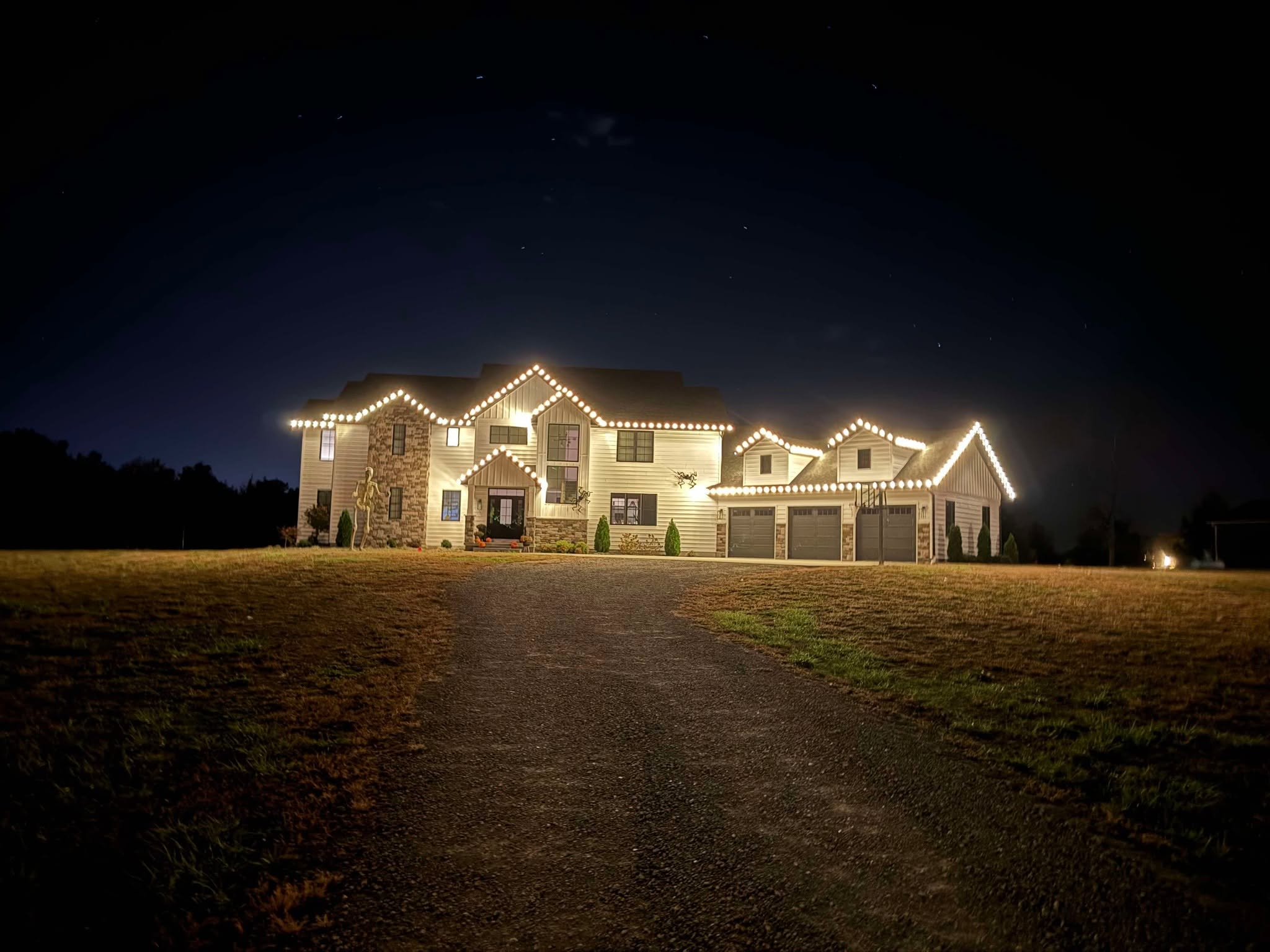 Country estate with warm white lights tracing the roofline