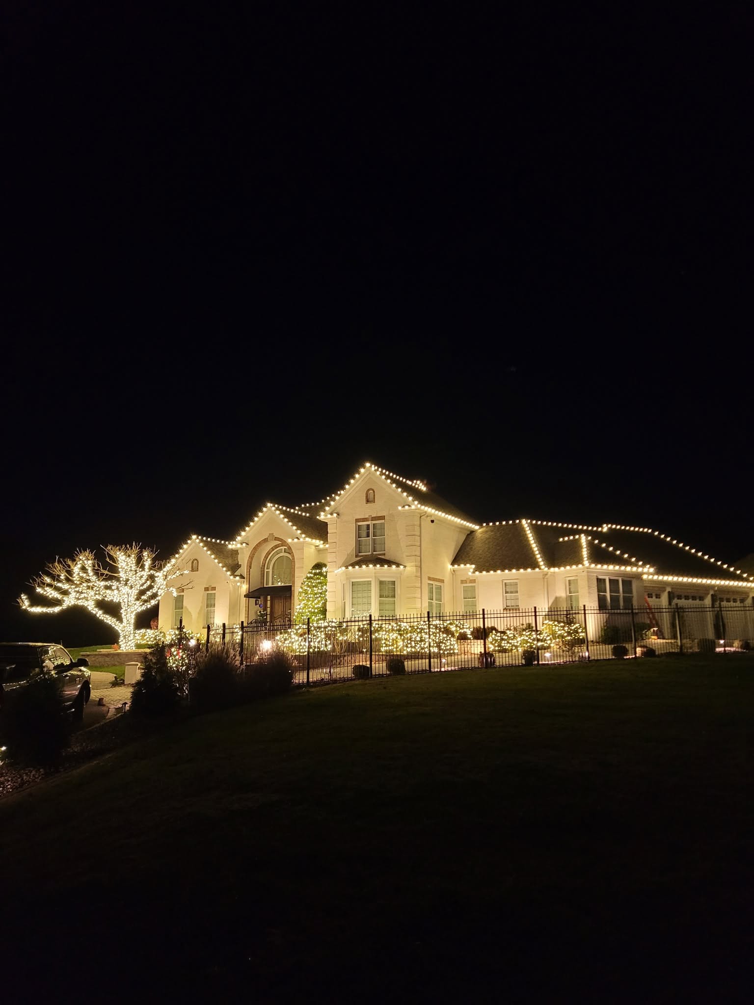 Large white estate outlined with warm white holiday lights