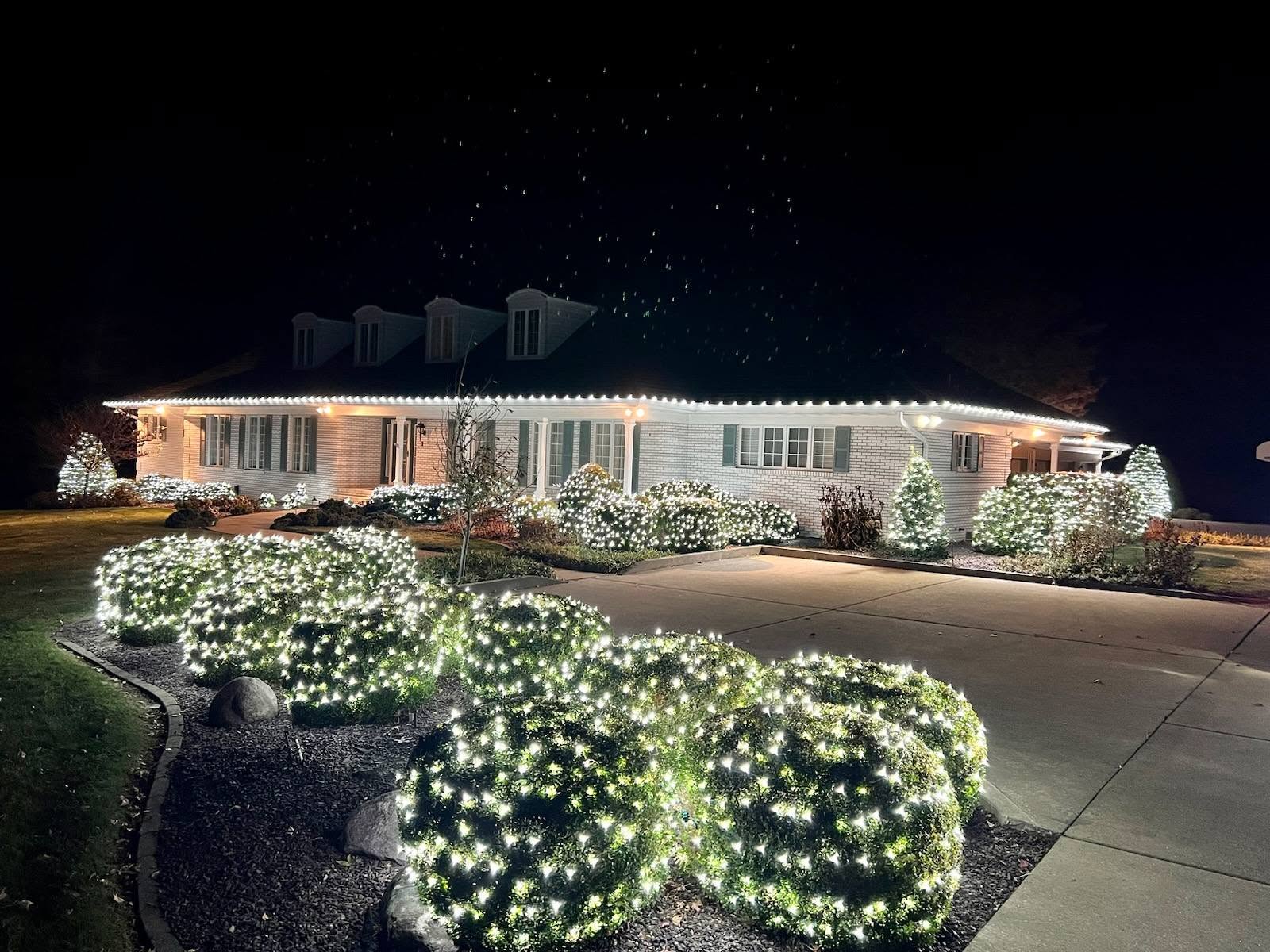 Home and landscaped shrubs covered in warm white holiday lights