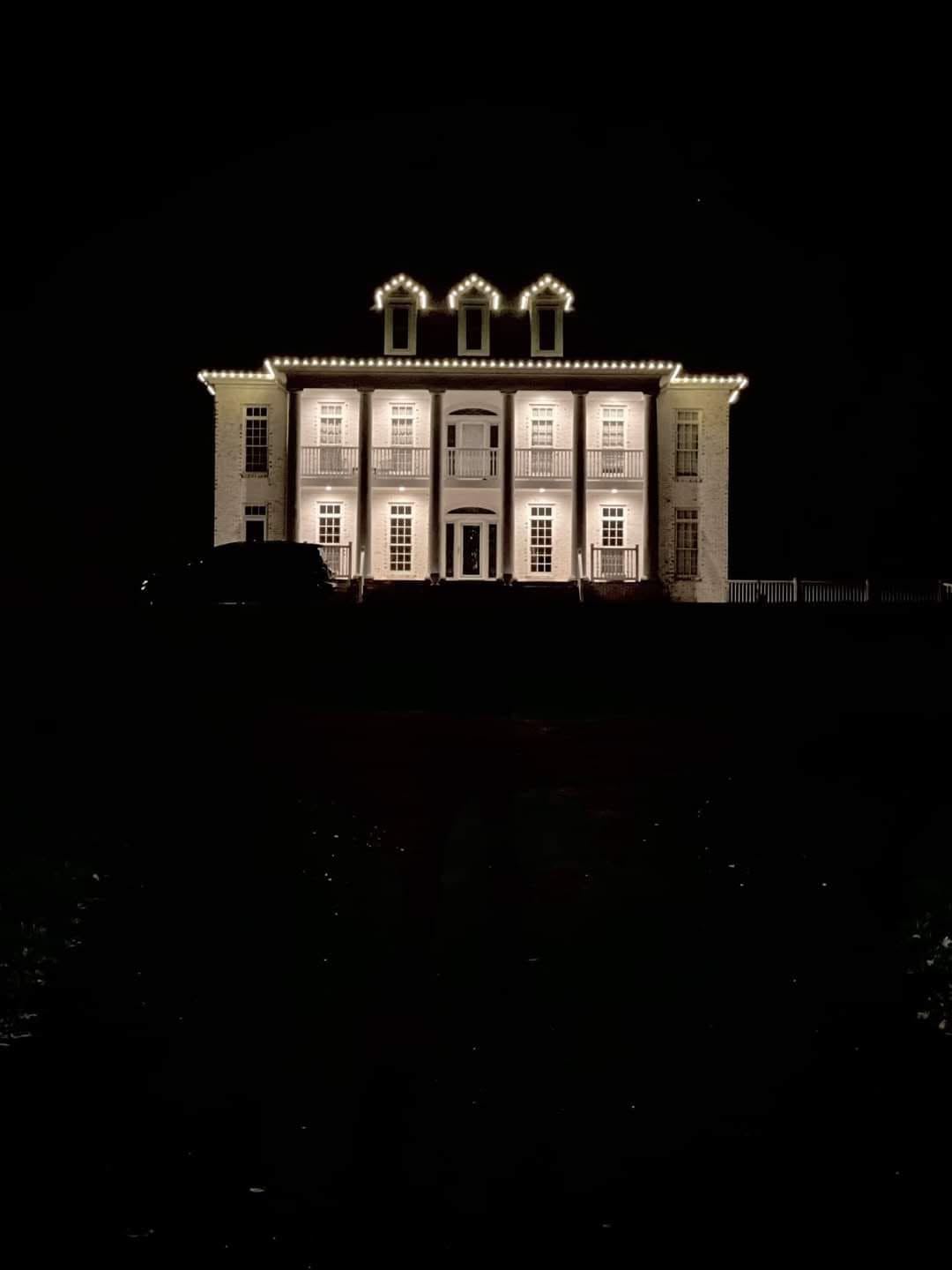 White column estate outlined in warm white holiday lights